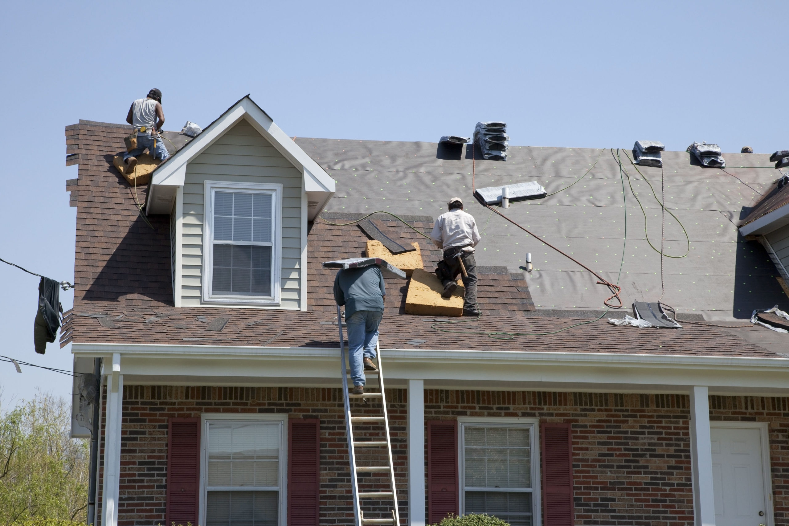 Roofers replacing damaged shingles after storm