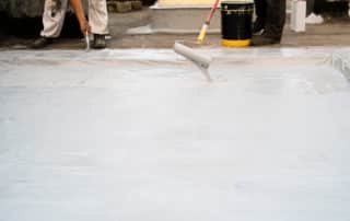 Two man applying material using the paint roller